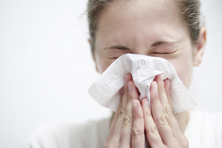 Frau schneuzt sich in ein Taschentuch. Allergie, Schnupfen, Rhinitis, Nase